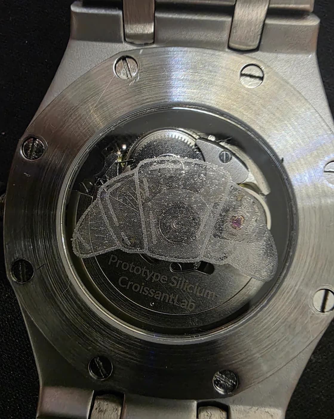 Fond de la montre vu de dessous : verre central qui laisse voir le mouvement automatique, croissant givré gravé et texte « Prototype Silicium CroissantLab ».
